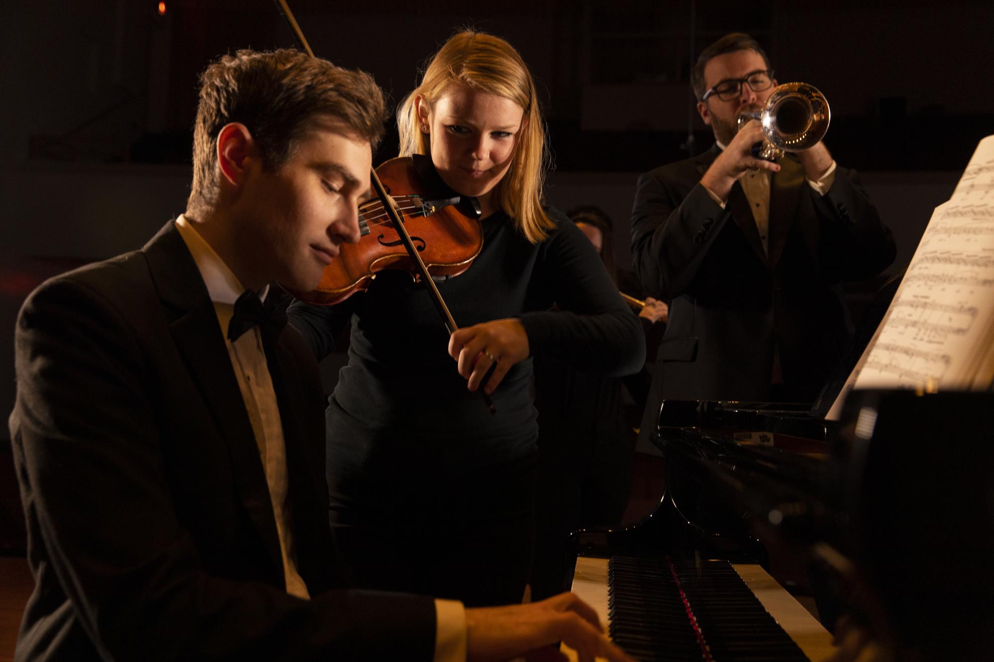 Three music students practicing piano, violin, and trumpet. 