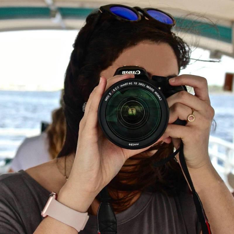 Front view of a student looking through the lens of her camera.