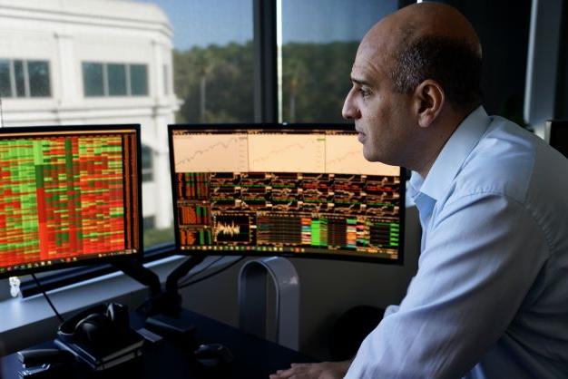 A close-up picture of an older male graduate student manipulating data at a desk with several computer monitors.