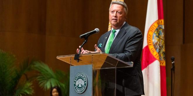 President Tim Cost addressing crowd at a podium.