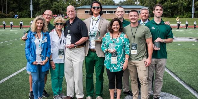 The seven alumni posing with their awards for their service as alumni of distinction.