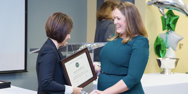 Whitney George embracing Dr. Sherri Jackson while accepting an award plaque for the 2019 Faculty Excellence Award