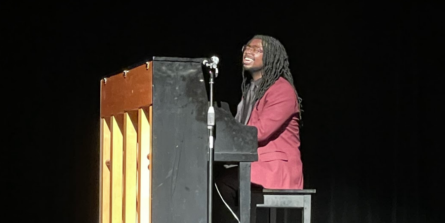 A male student musician singing while playing the piano.